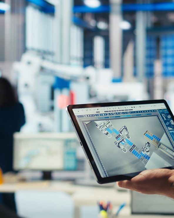 Engineer in photovoltaics factory uses tracking software on tablet to review performance of robot arms manufacturing solar panels. Expert uses device to inspect solar plant machinery, camera A closeup